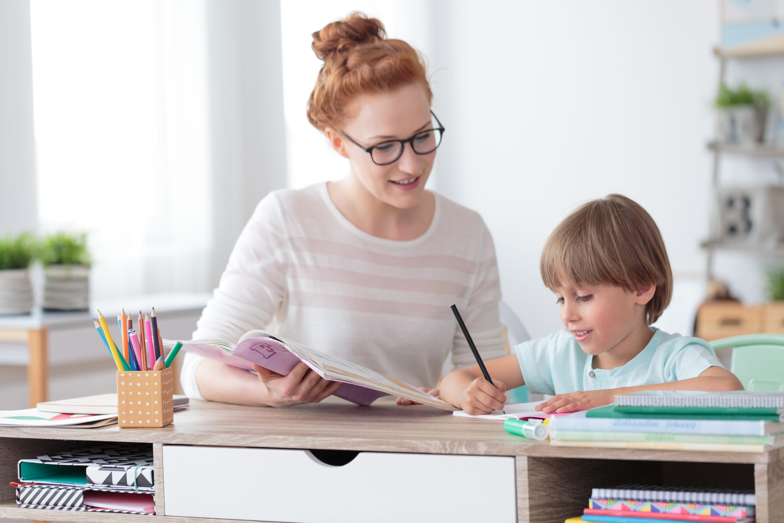 Female,Private,Tutor,Helping,Young,Student,With,Homework,At,Desk